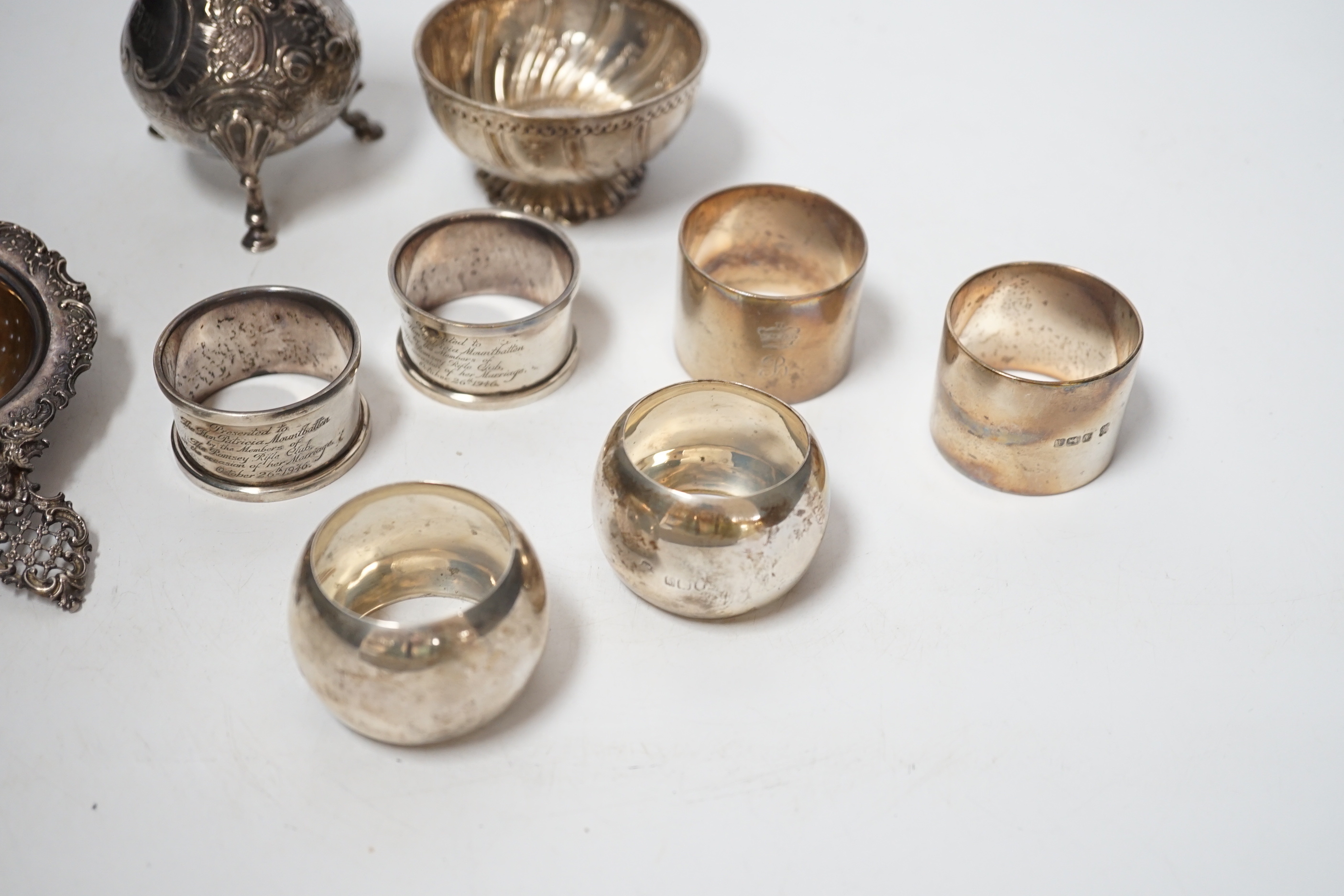 Sundry silver including six silver napkin rings, an 800 standard tea strainer and a white metal bowl and cream jug.